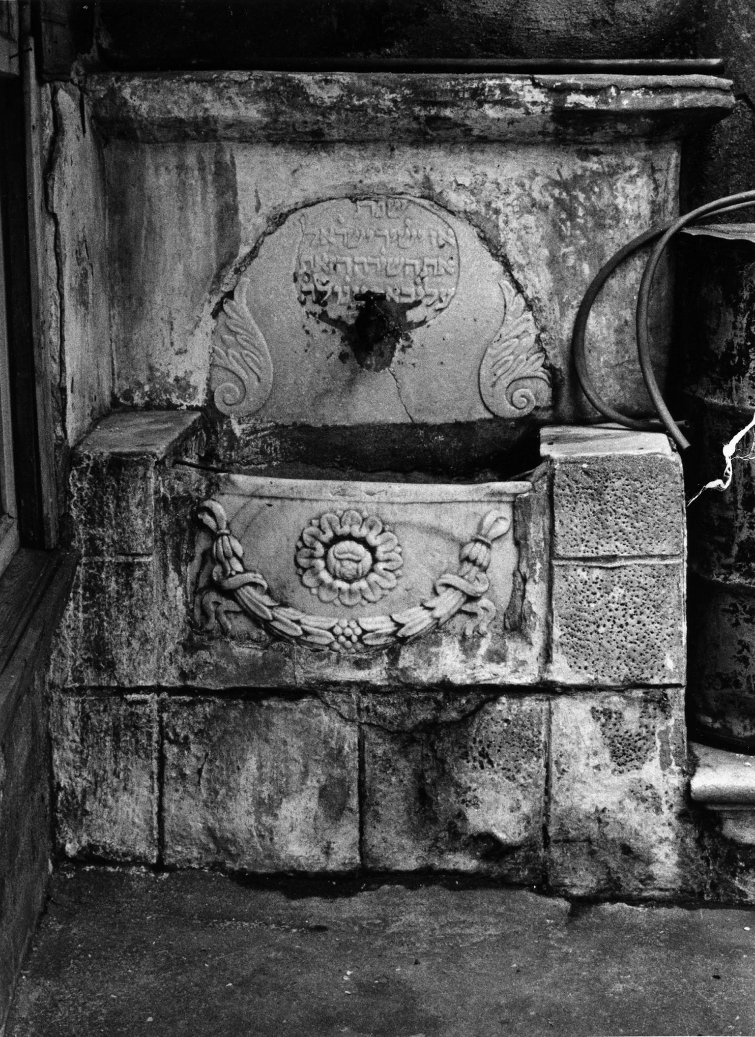 Photograph of basin with floral motif and Hebrew engraving. 
