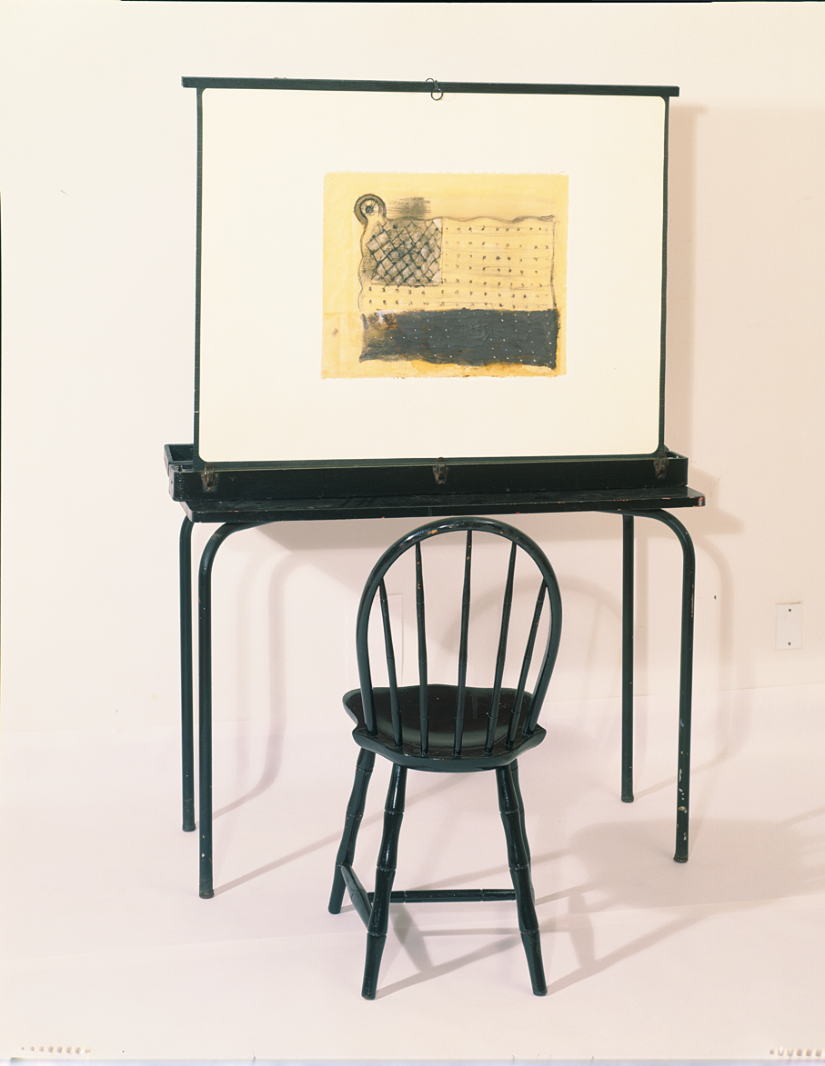 Sculpture of empty chair at desk that holds up a painting resembling a flag.