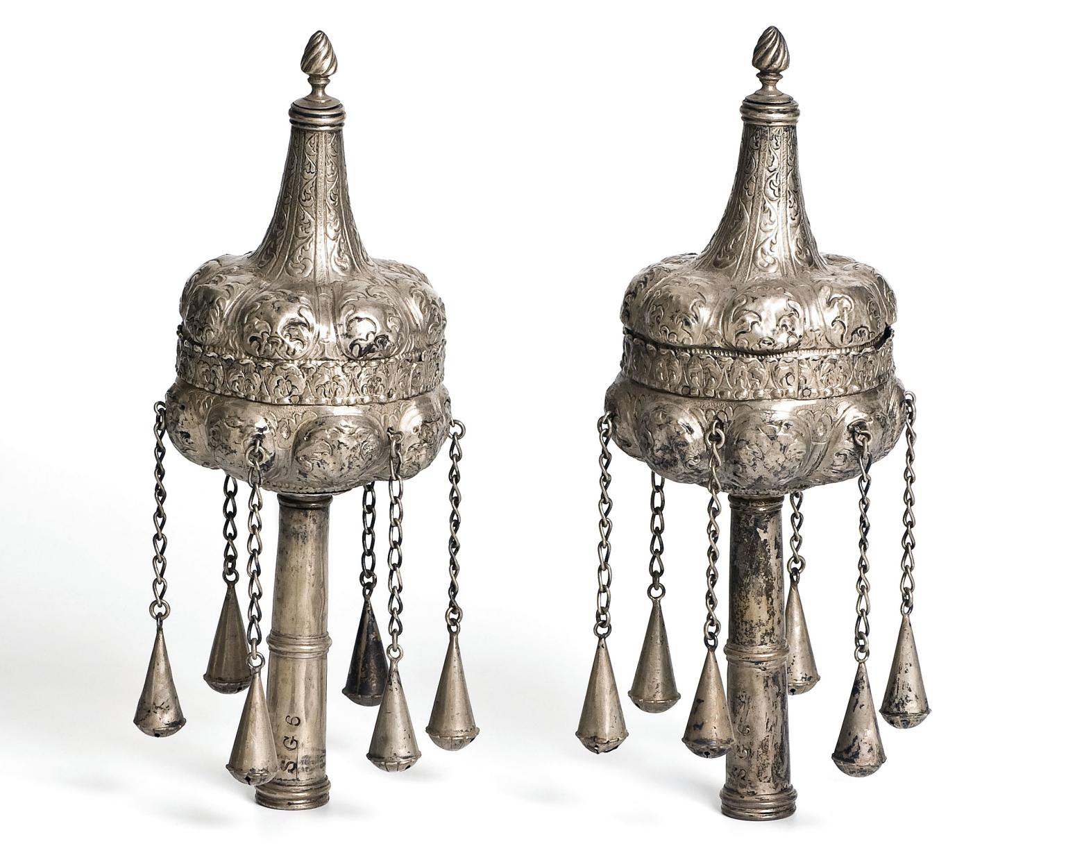 Pair of finials with decoration and chains hanging down. 