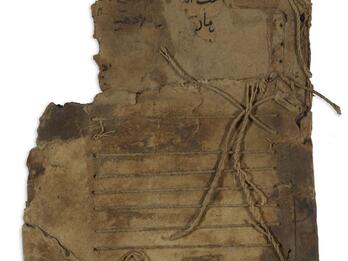 Worn, thick sheet of paper with Arabic script toward the top and string below woven through, creating parallel lines.