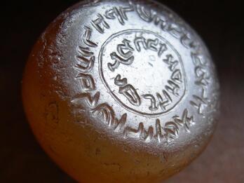 Photo of a rounded orange object inscribed with reversed Hebrew writing in concentric circles, viewed at an angle.