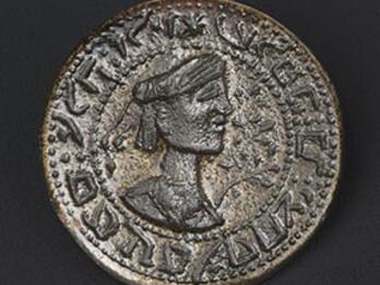 Round bronze seal with a turbaned bust in profile and floral decoration, encircled by reversed Hebrew text.