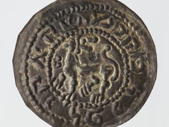 Tarnished silver coin with a stylized lion in the center, encircled by a Hebrew inscription.