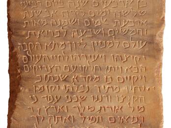 Peach-colored marble tablet engraved with sixteen lines of Hebrew script.