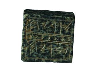 Square rock seal decorated with lines and dots that surround a Hebrew inscription.