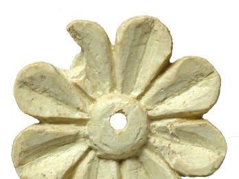 Ivory carving in shape of an eight-petaled flower with small hole in center.