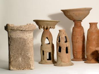 Ritual containers including stone altar, two offering bowls on tall bases, four chalices, and two stands with cylindrical bases. 