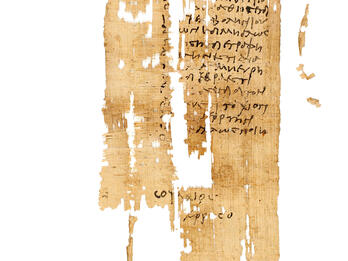 A fragment of ancient, worn papyrus with faded Greek writing in black ink. The document is yellowed and torn in several places, with large missing sections and frayed edges.