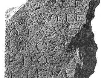 A stone fragment inscribed with ancient Greek text in several lines. The edges are irregular and broken.