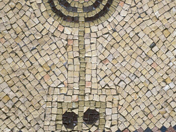 Ancient mosaic depicting a menorah with seven branches made from colored tiles, set against a beige background with geometric patterns.