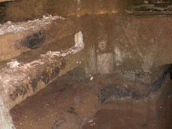 A stone chamber with carved shelves and niches along the walls, showing signs of age and wear.