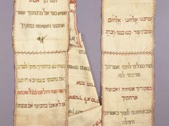 Rectangular cloth arranged in two columns embroidered with Hebrew text and small Star of David on right side. 