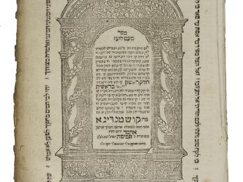 Printed page of Hebrew text framed by arch with columns of garlands and a border of Hebrew text.