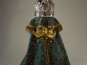 Cloth cover with embroidery and metal crown, and crown resting on top of cloth. 