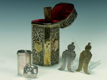Set of objects: a box lined with velvet, a small box with lid next to it, and two small shields. 