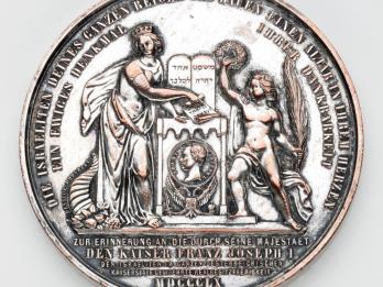 Medal depicting two figures on either side of a set of tablets and small portrait of man in center.