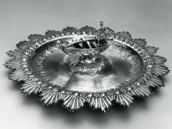 Silver plate featuring a boat in the center. 