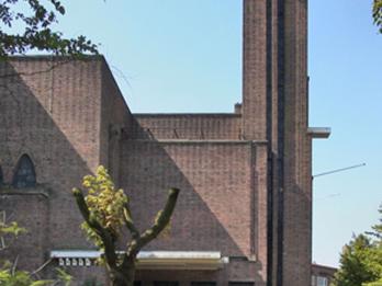 Photograph of brick facade and block shaped tower of building.