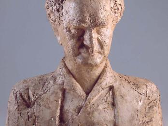 Bust sculpture of an elderly man with central bald spot facing viewer.