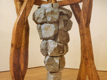 Sculpture of iron grape cluster hanging on wooden framework.
