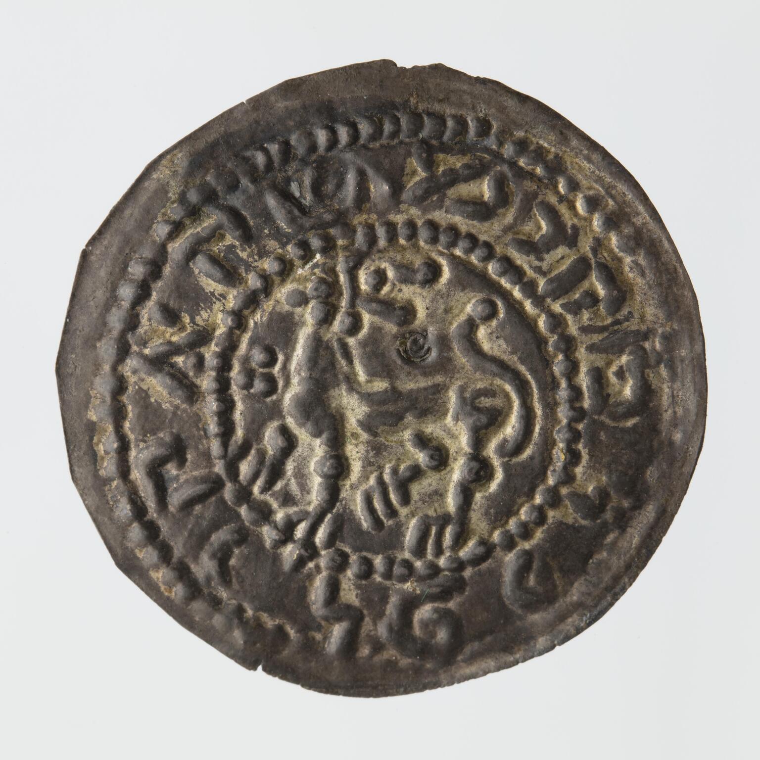 Tarnished silver coin with a stylized lion in the center, encircled by a Hebrew inscription.