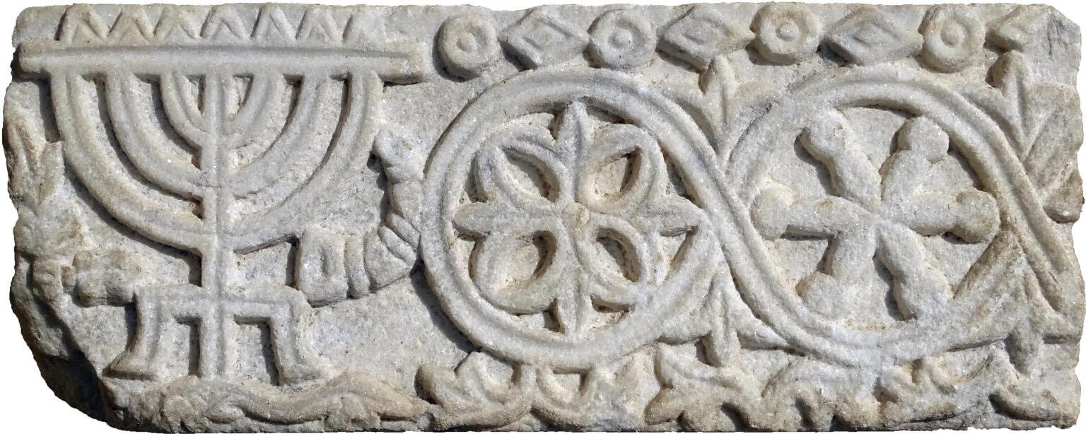 Stone relief featuring a candelabrum, horn, and plant bundle, floral patterns, and floral and geometric borders.