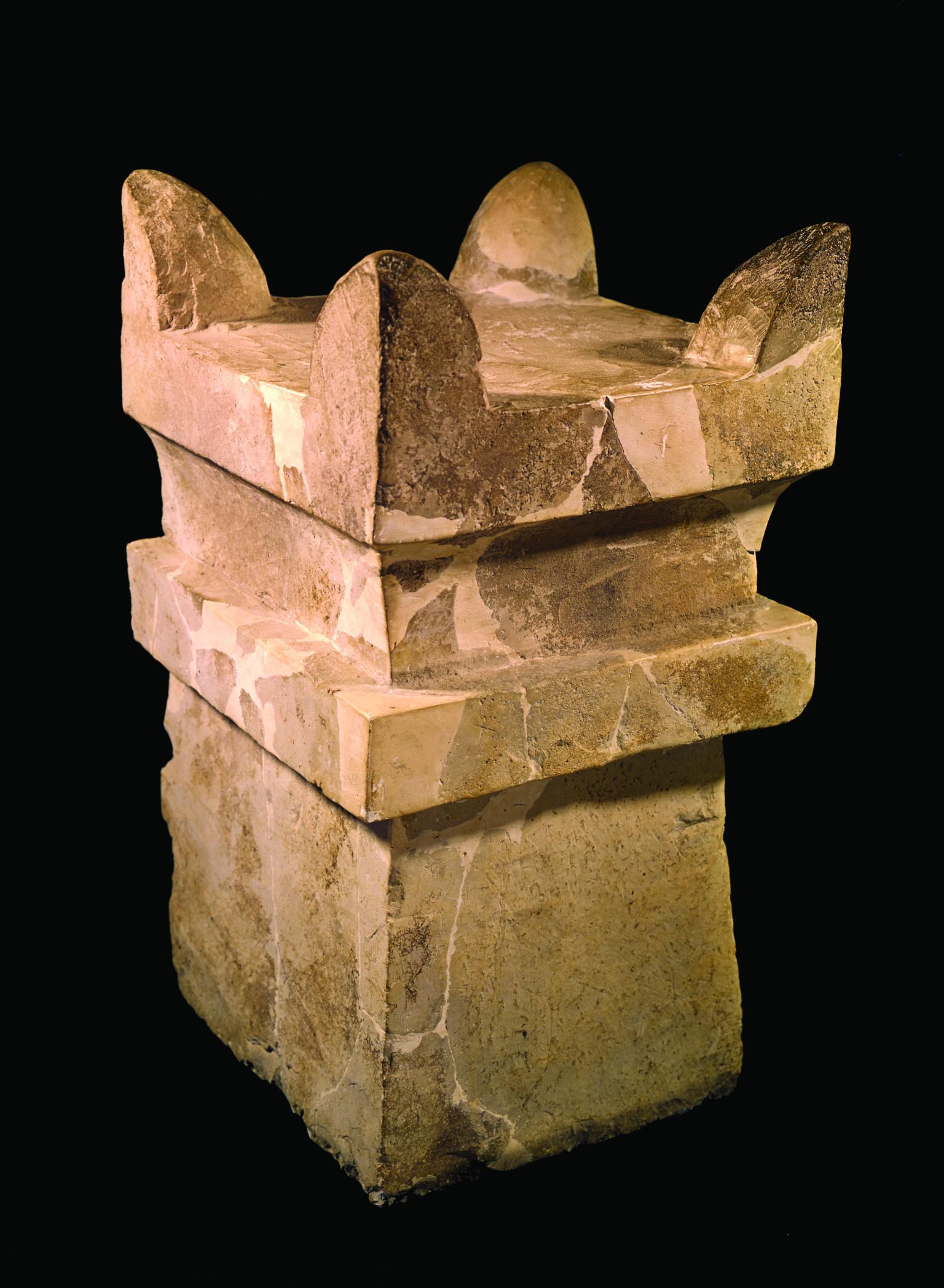 Square limestone altar with horns at four upper corners and recessed band below offering surface.