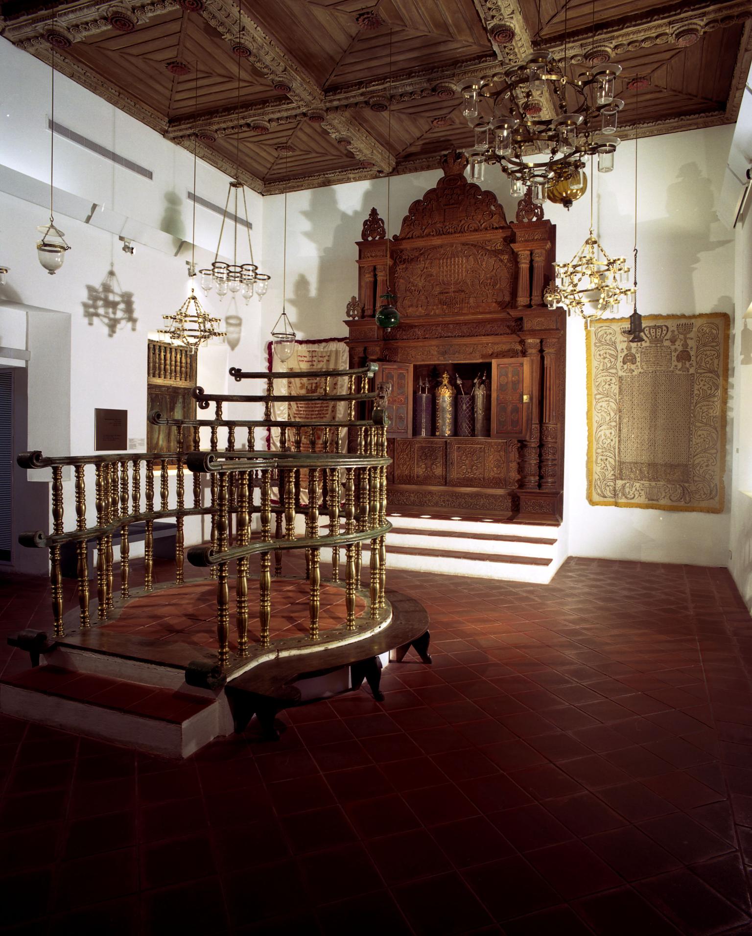 Photograph of room with raised wood platform in middle and wooden Torah ark in far wall.