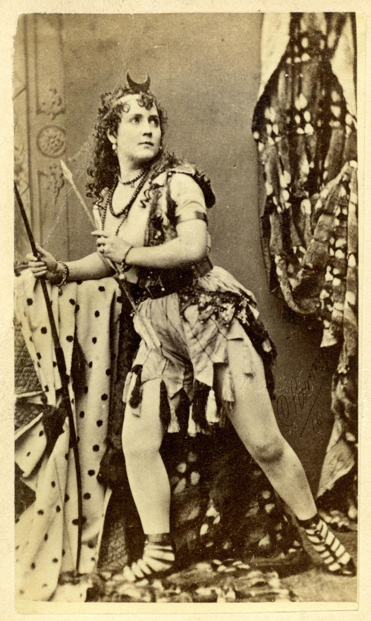 Full body portrait of woman with legs slightly bent and body shifted to one side in an active pose, wearing armor. 