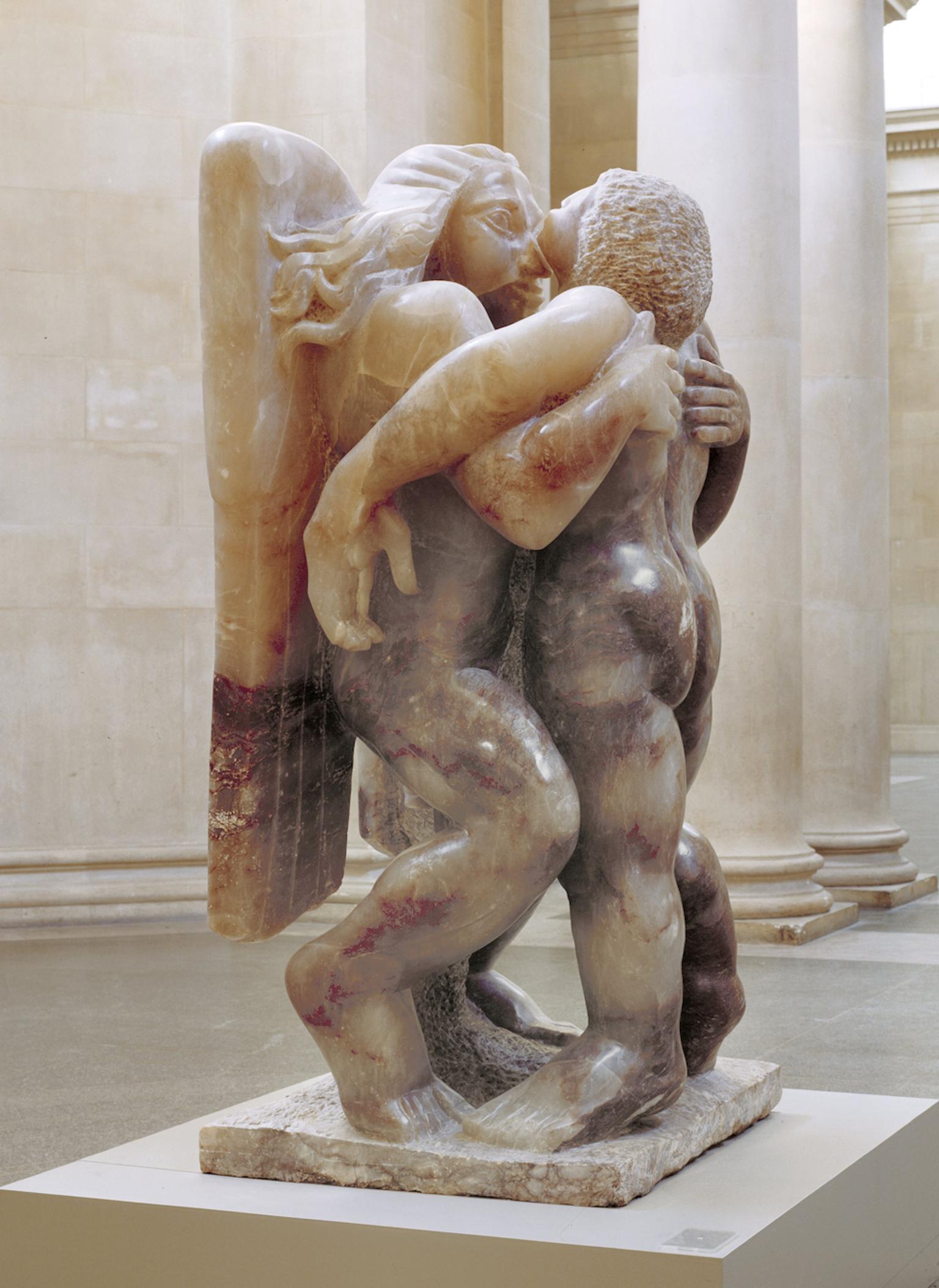 Sculpture depicting angel and man, both upright, with arms around each other.