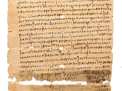 Ancient, weathered papyrus manuscript with lines of Greek text, featuring some holes and missing sections at the bottom.
