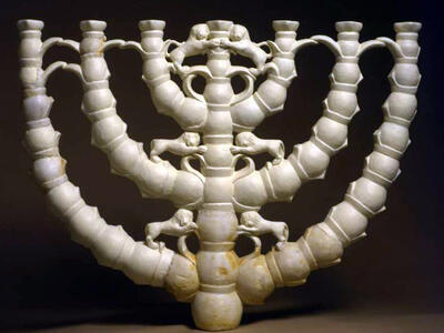 White menorah with seven branches, each decorated with lion figures and intricate connecting elements.