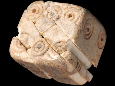 A carved ivory cube engraved with concentric circles.