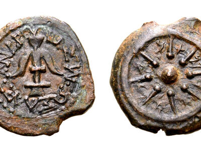 Two sides of an ancient coin: one side shows an anchor surrounded by a Greek inscription, and the other shows a small circle with eight rays radiating from it within a larger circle. Paleo-Hebrew letters are inscribed between the rays.