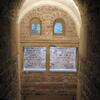 Photo of a stone stairway descending to an arched alcove with two arched windows above a larger rectangular window.