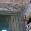 Photo of a rectangular stone and brick pool partially filled with water, with a stairway descending into it and an arched door.