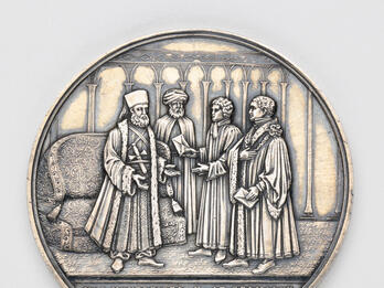 Silver medal depicting four men talking.