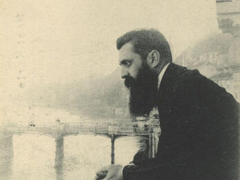 Photograph of man leaning over a bridge.