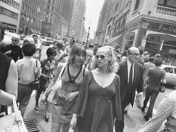 Photograph of two women walking down busy city street toward photographer. 