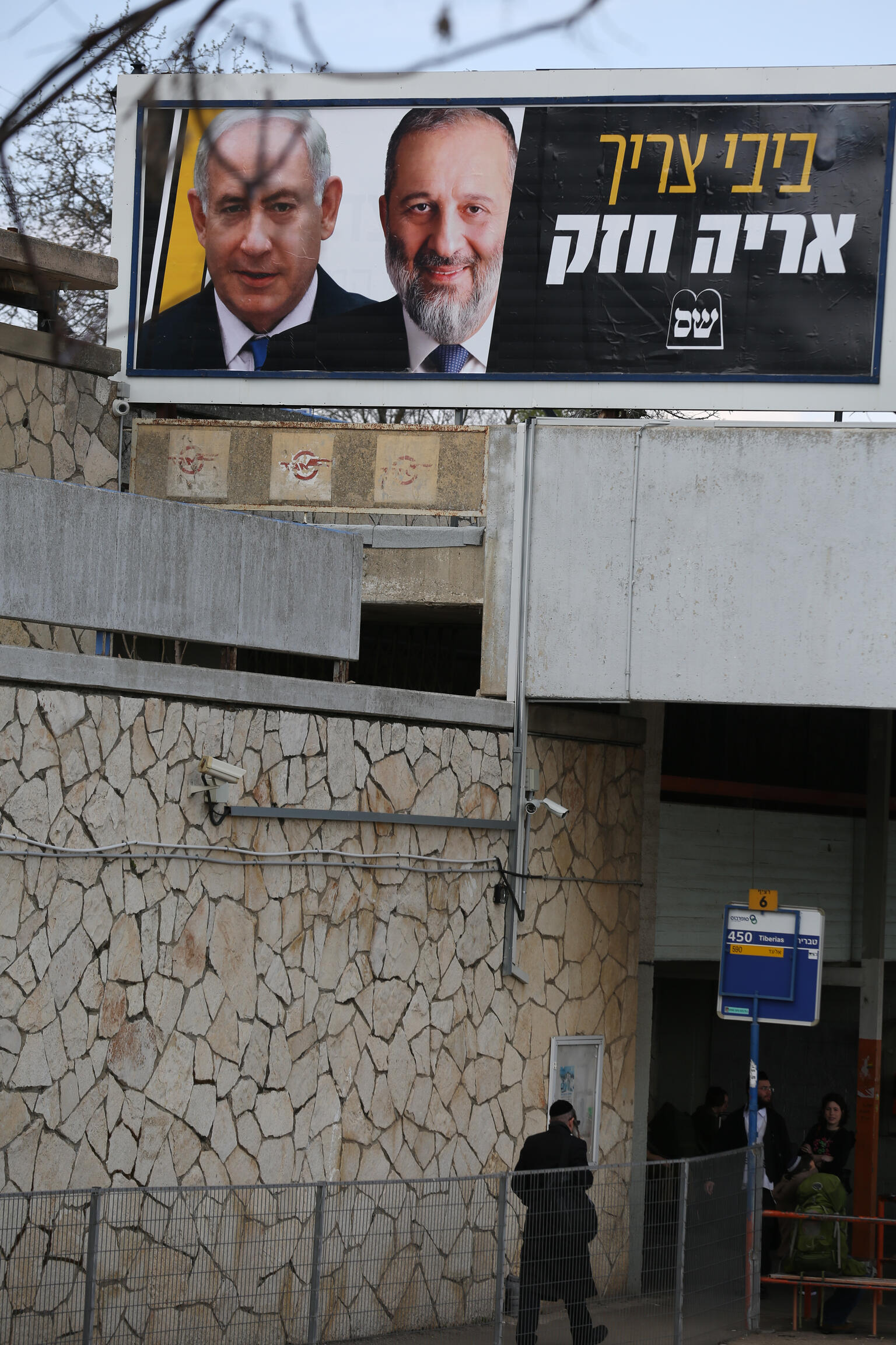 Campaign poster on an overpass with side-by-side pictures of Benjamin Netanyahu and Aryeh Deri beside the Hebrew words ביבי צריך אריה חזק