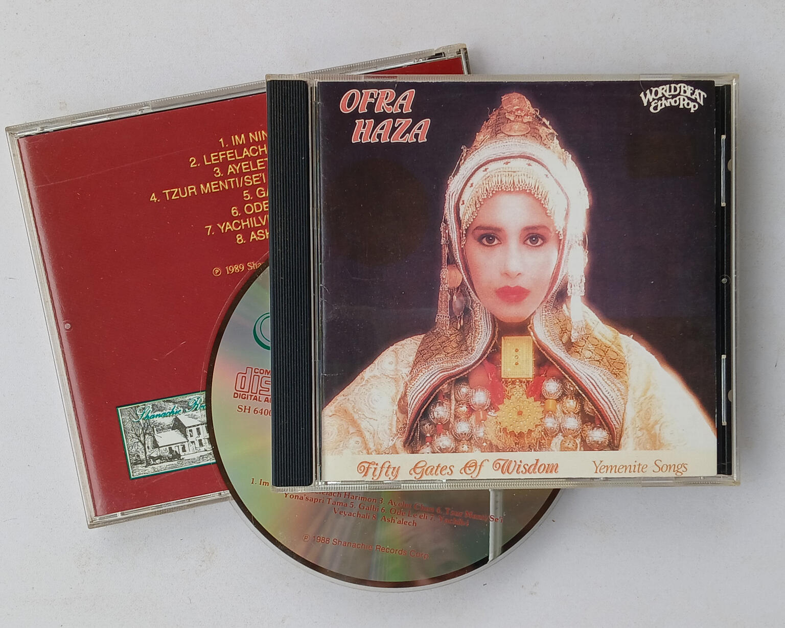 Front and back of CD case with CD. The front has a picture of a woman in Yemenite dress, with the words "Ofra Haza" on the top left, and "Fifty Gates of Wisdom" and "Yemenite Songs" on the bottom.