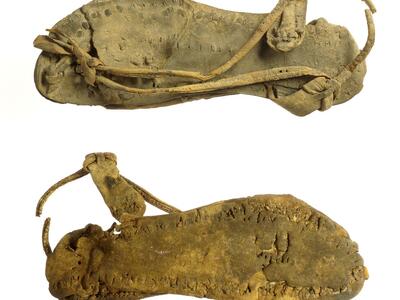 Two views of a single leather sandal. 