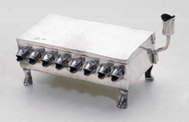 Silver rectangular lamp with fish-head spouts for the oil and paw-shaped feet.