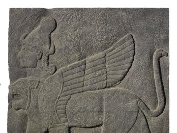 Stone relief of winged lion-like figure with extra head wearing headdress.