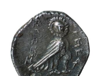 Coin with image of owl with body facing right and face turned towards the viewer and Hebrew inscription.