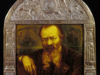 Painting of man in beard and glasses set inside an ornate frame with decorated border. 