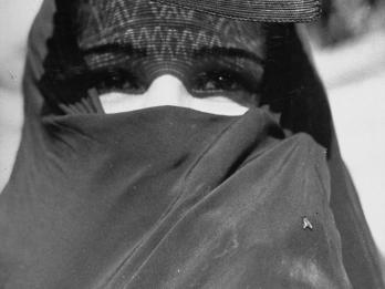 Photograph of veiled woman facing viewer with only her eyes exposed.