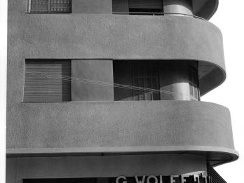 Photograph of side of three-story building exterior featuring sleek, curved balconies.