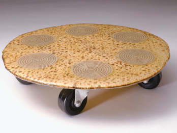 Matzah and paper in epoxy resin on wheels with six spirals made of typeset text on top of matzah. 