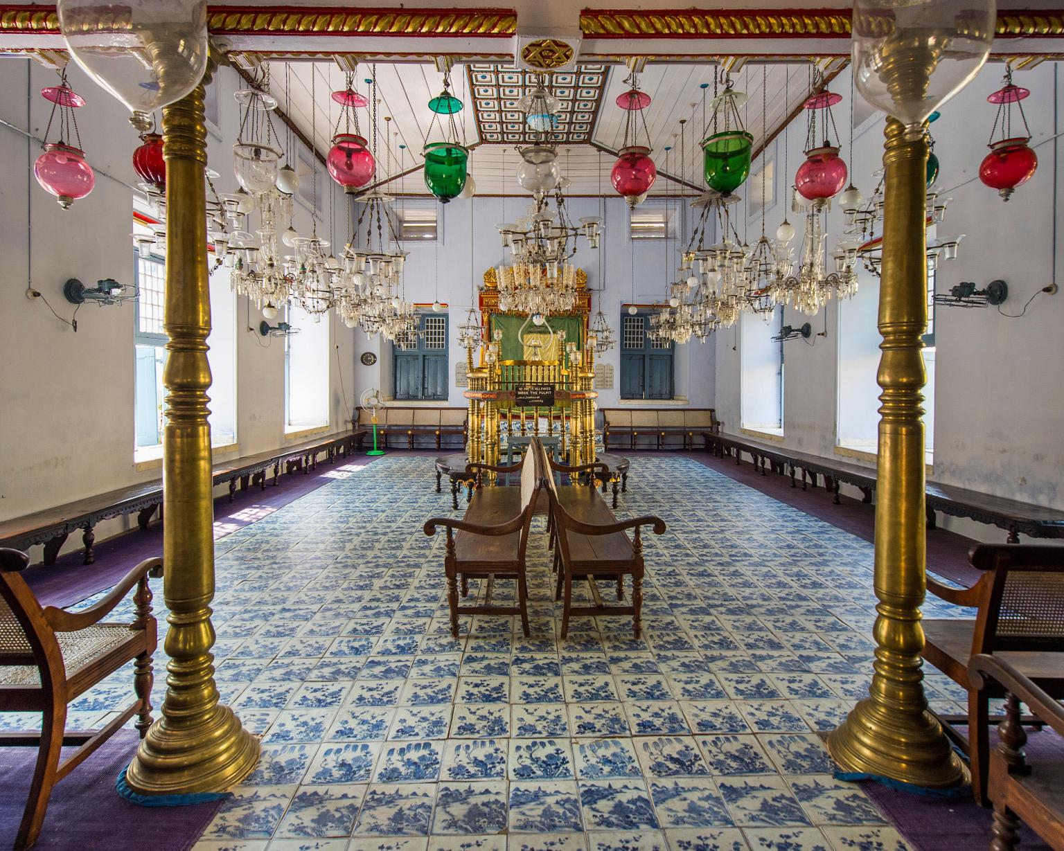 Photograph of room with floor tiles, two gold columns, and glass chandeliers.